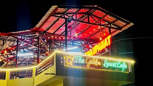 Un bâtiment sur lequel on peut voir une enseigne au néon indiquant : « Le Café des Feuilles d’Or ».