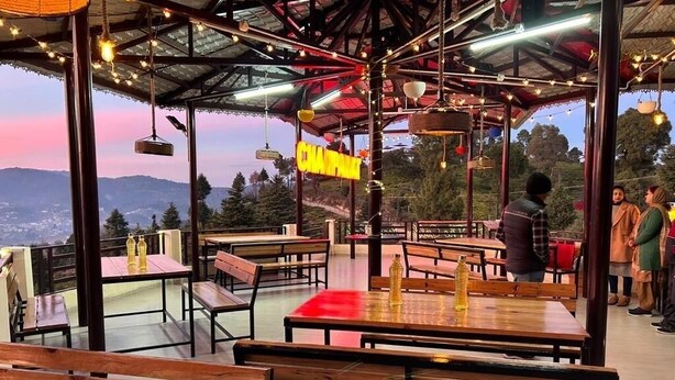 Un restaurant en plein air avec des tables et des bancs en bois, une vue sur les montagnes et une enseigne sur laquelle on peut lire « CHAPAL ».