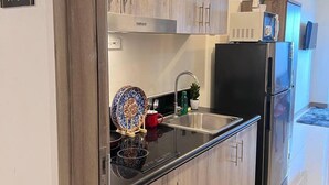 A modern kitchen with wooden cabinets, a stainless steel refrigerator, and a black countertop. - Unistay Coast Res R31 with Bal-Sunset Vw (Pasay)