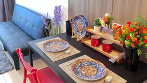 A dining area with a table set for two, featuring patterned plates and a vase of flowers. - Unistay Coast Res R31 with Bal-Sunset Vw (Pasay)
