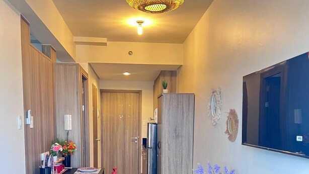 A modern kitchen with a dining table, red chairs, a black sofa, and a decorative plant. - Unistay Coast Res R31 with Bal-Sunset Vw (Pasay)