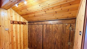 A wooden-paneled room with a large wardrobe, a light switch, and a ceiling light fixture. - Leo's House (Carbonare)