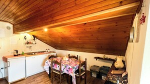 A kitchen with wooden ceiling, a dining table with chairs, and a refrigerator. - Leo's House (Carbonare)