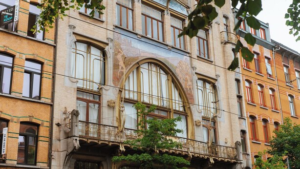 Un edificio histórico con múltiples ventanas y balcones, destacando detalles arquitectónicos intrincados y un mural.