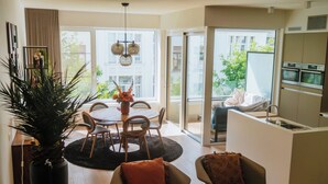 Una sala de estar moderna con comedor, cocina y puerta corrediza de vidrio que da a un balcón exterior.