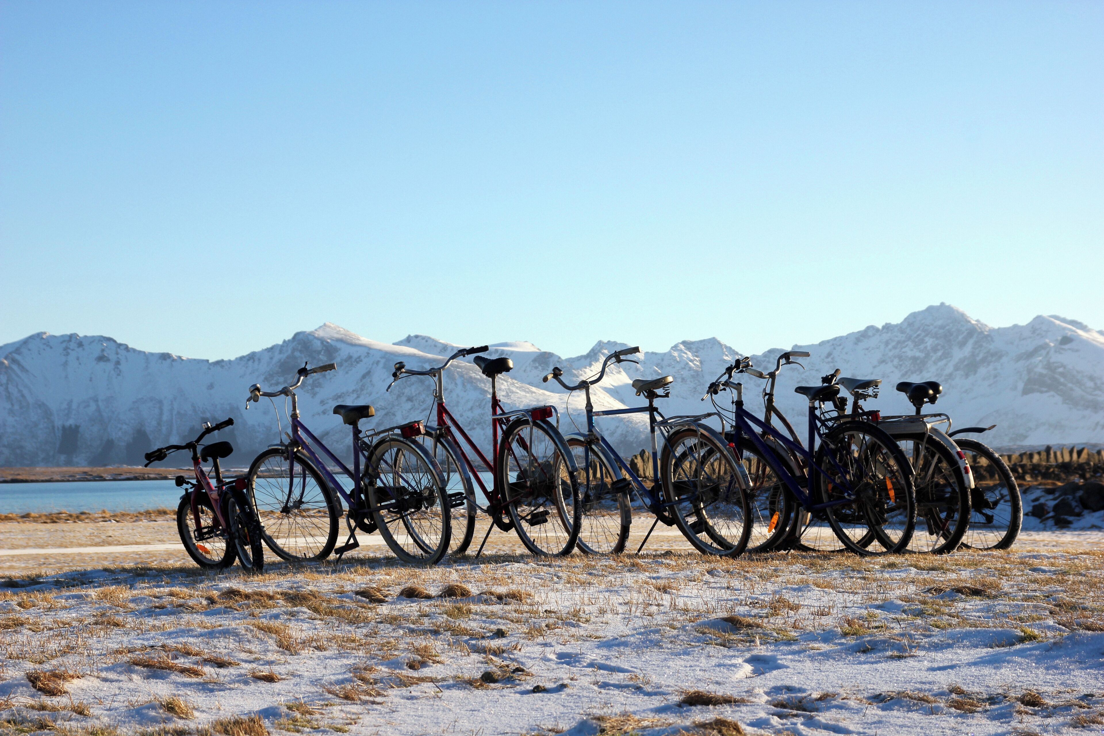 Bicycles parked in a snowy field with mountains in the background.