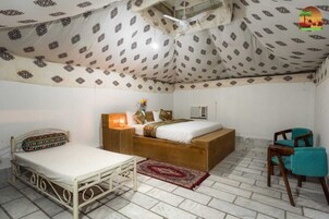Una habitación con cama, mesita de noche, una silla y techo con diseño.