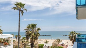 Blick auf einen Strand mit Palmen, einem klaren Himmel und ruhiger See.
