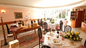 A dining area with round tables, chairs, a wooden buffet, and a wine rack. - hotel san gerolamo (Vercurago)
