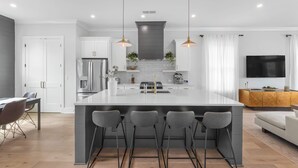 Une cuisine moderne dotée d’un îlot central, de luminaires suspendus et d’un four encastré.