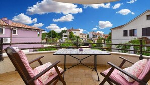 A balcony with a table and chairs, overlooking a residential area with houses and greenery. - Charming accommodation with shared pool Beahost (Peroj)