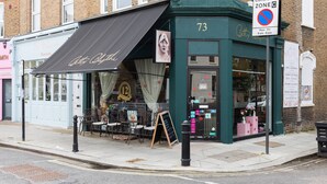 A restaurant with outdoor seating, a sign indicating a controlled zone, and a number 73 on the building. - Caithness Road VI by Onefinestay (London)