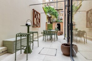 A courtyard with a dining area, a green metal bench, and a potted plant. - Culford Gardens III by Onefinestay (London)