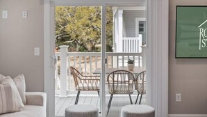 En stue med en skydedør, der fører ud til en balkon med fletstole og skamler.