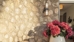 A stone wall with a light fixture and a vase of flowers. - Hotiday Room Collection - Massa Lubrense (Massa Lubrense)