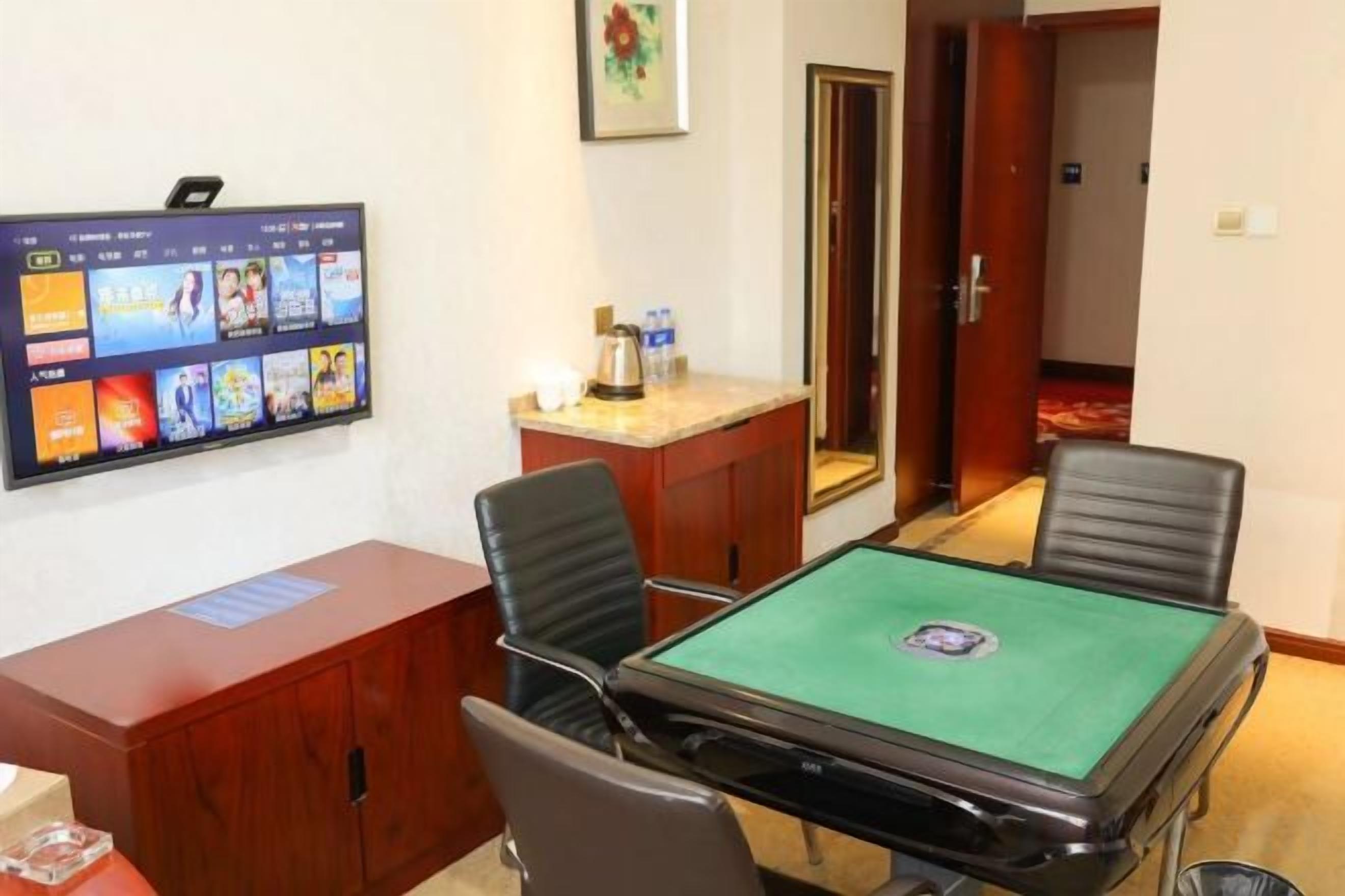 Une salle de conférence équipée d’une table, de chaises, d’un bureau, d’un téléviseur et d’une porte donnant sur une autre pièce.