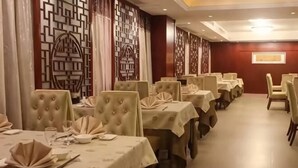 A dining area with multiple tables, each set with chairs and tablecloths. - Zhoushan Perfect Business Hotel (Zhoushan)