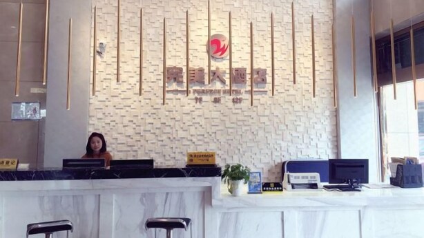 A hotel reception desk with a modern design, featuring a brick-patterned wall and a logo above the counter. - Zhoushan Perfect Business Hotel (Zhoushan)
