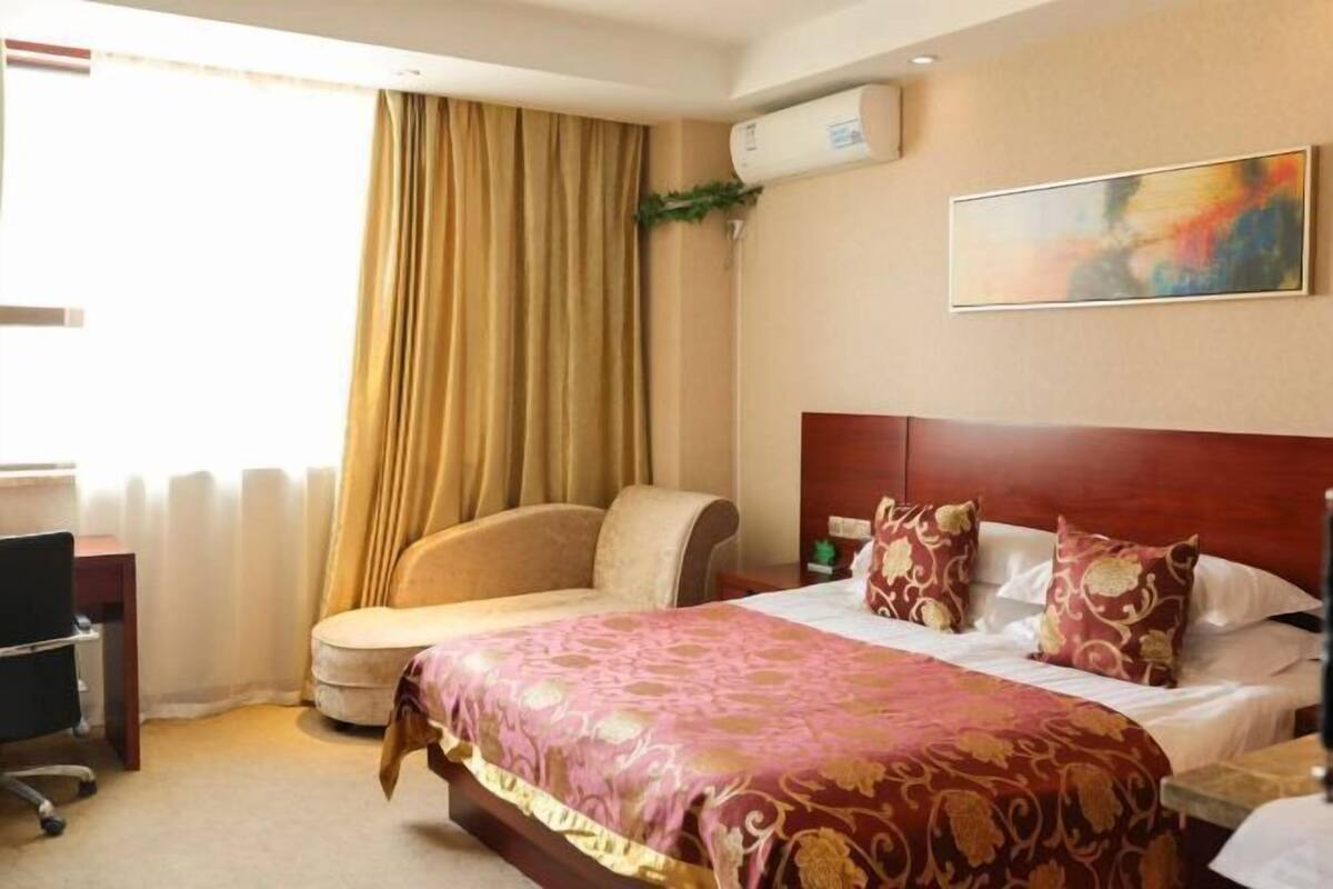 A hotel room with a bed, a desk, and a chair.