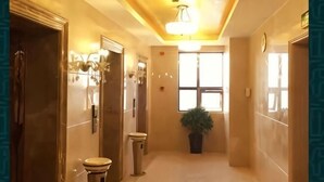 A hotel corridor with a polished floor, a potted plant, and a large window at the end. - Zhoushan Perfect Business Hotel (Zhoushan)