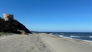 Ein Sandstrand mit einer Steinarchitektur auf einer Klippe.