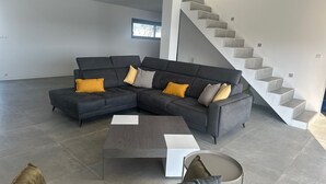 Ein modernes Wohnzimmer mit einer Eckcouch, einem Couchtisch und einer Treppe.