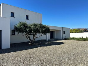 Ein modernes Gebäude mit Kiesweg, Baum und blauem Himmel.