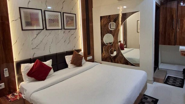 A modern bedroom with a large bed, a ceiling fan, and a mirror above the bed. - Hotel Sapphire Inn (Gorakhpur)