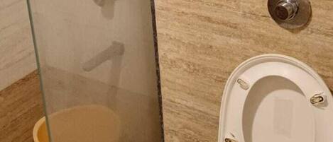 A bathroom with a glass-enclosed shower, a toilet, and a towel rack.