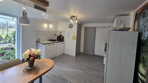 Une cuisine moderne avec des meubles blancs, une table à manger en bois et un réfrigérateur.