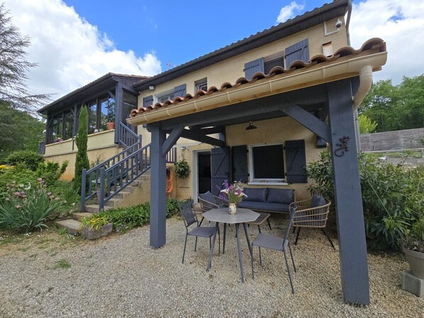 A house with a covered patio, a staircase, and outdoor seating.