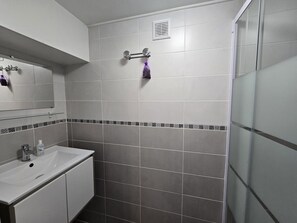A bathroom with a white sink, mirror, and a shower area.