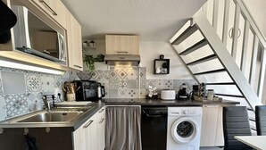 Una cocina compacta con lavadora, microondas y cafetera.