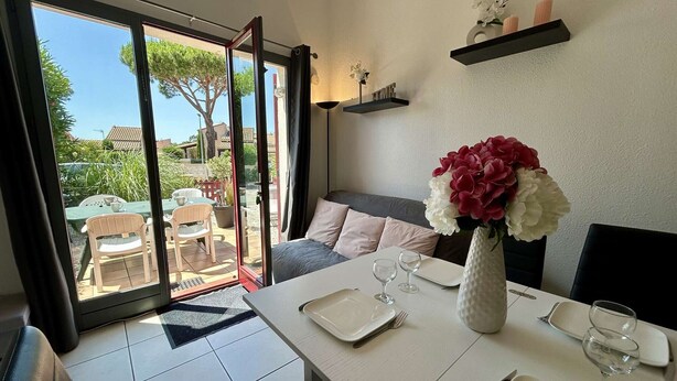 Un comedor con una mesa lista para dos, un sofá y vistas al exterior.