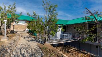 A building with a green roof, stone walls, and a paved pathway leading to a gated entrance.