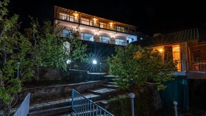 Un edificio de varios pisos con una escalera que lo conduce, rodeado de vegetación.