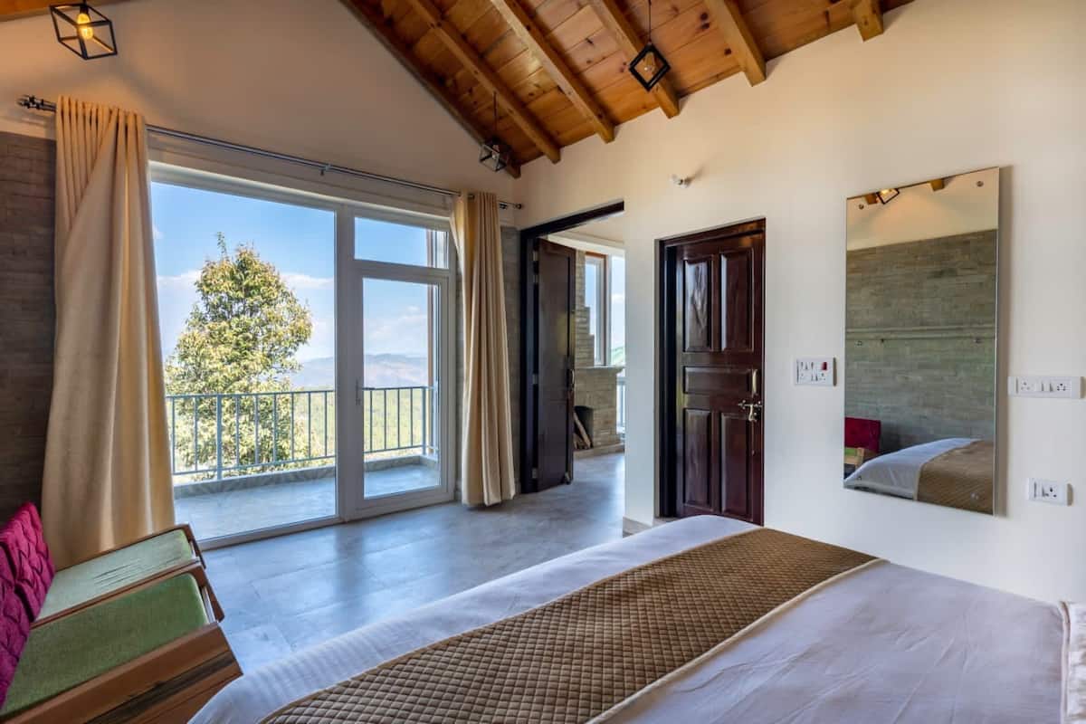 A spacious bedroom with a large bed, a view of the outdoors, and a wooden ceiling.
