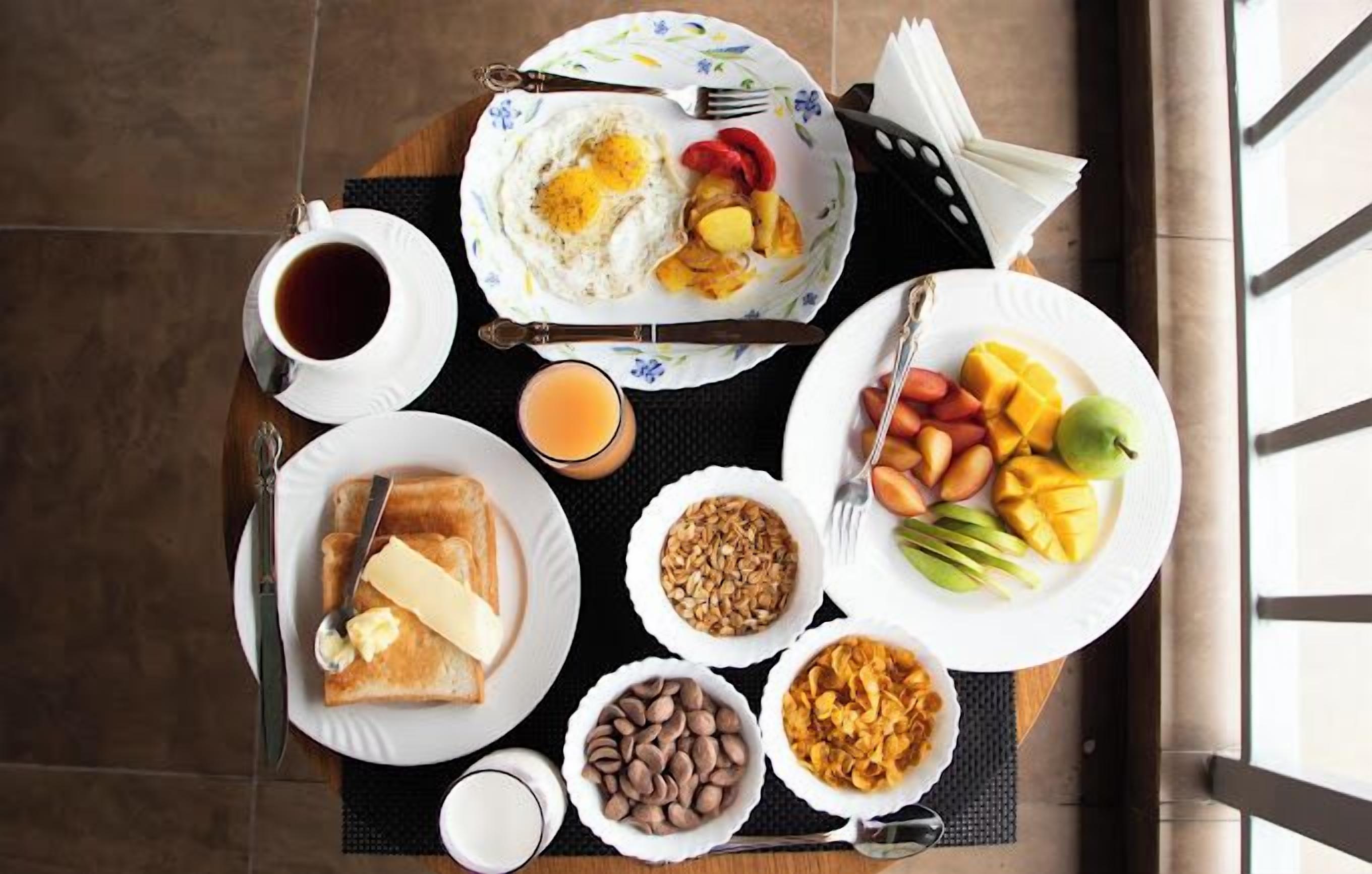 A breakfast setup with toast, eggs, fruit, and various spreads on a tray.