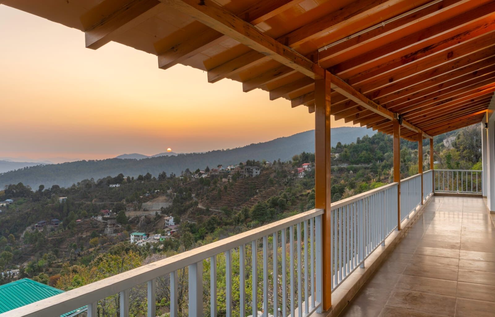 Un balcón cubierto con vistas a un paisaje montañoso al atardecer.