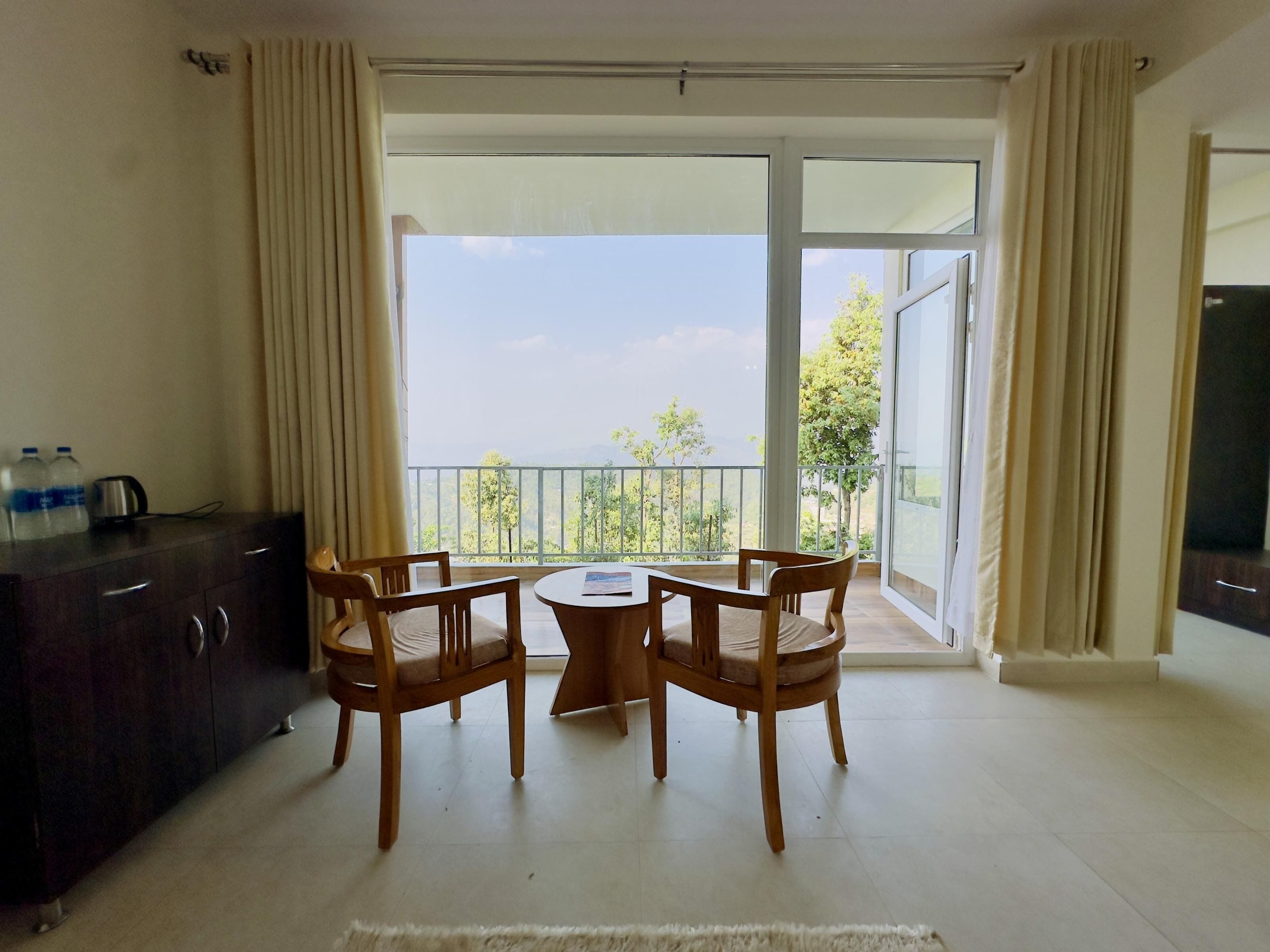A room with a balcony, a dining table with chairs, a cabinet, and a television.