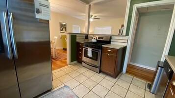 A compact kitchen with a refrigerator, stove, oven, and a small cabinet.