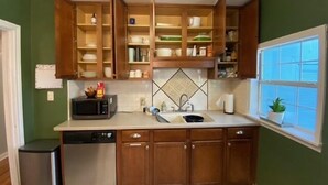 Une cuisine avec des meubles en bois, un four à micro-ondes, un évier et une fenêtre avec des stores.