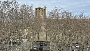Un parcheggio con diverse auto e un edificio storico sullo sfondo.