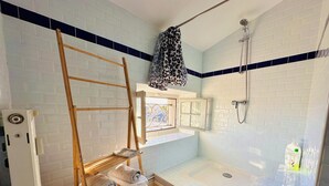 Un bagno con doccia, asciugamano e finestra vista.