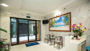 A hotel lobby with a reception desk, seating area, and a large painting of a beach scene. - Sumitomo7- Linh Lang Serviced Apartment (Hanoi)
