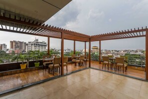 A rooftop terrace with wooden pergolas, seating, and potted plants. - Hotel Surya Grand (Lucknow)