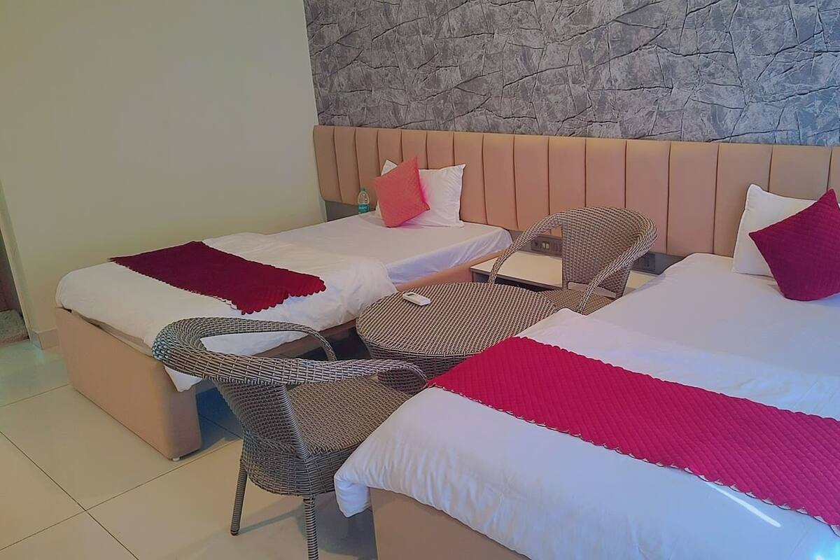 Ett hotellrum med två sängar, flätade stolar och en vägg av sten.