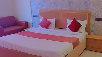 Un dormitorio con cama, mesita de noche, sofá rojo y ventilador de techo.