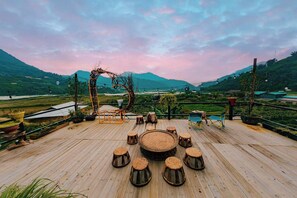 A wooden deck with a circular seating area and a rustic arch structure. - Alu Homestay Ta Phin (Ta Phin)