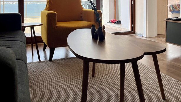 A modern living room with a yellow armchair, a round coffee table, and a view of the sea through large windows. - Stay with the best view of Izmir (İzmir)